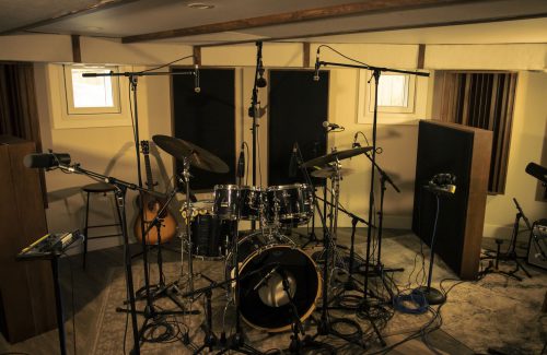 A drum set that is set up to record with microphones.